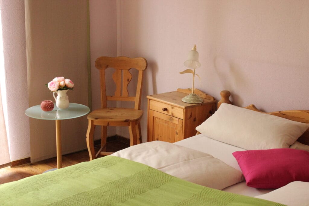 Gemütliches Schlafzimmer mit Holzstuhl und Beistelltisch.