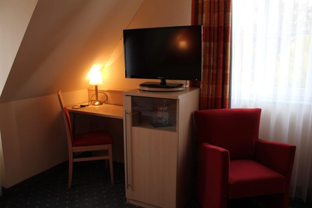 Hotelzimmer mit Schreibtisch, Stuhl und Fernseher